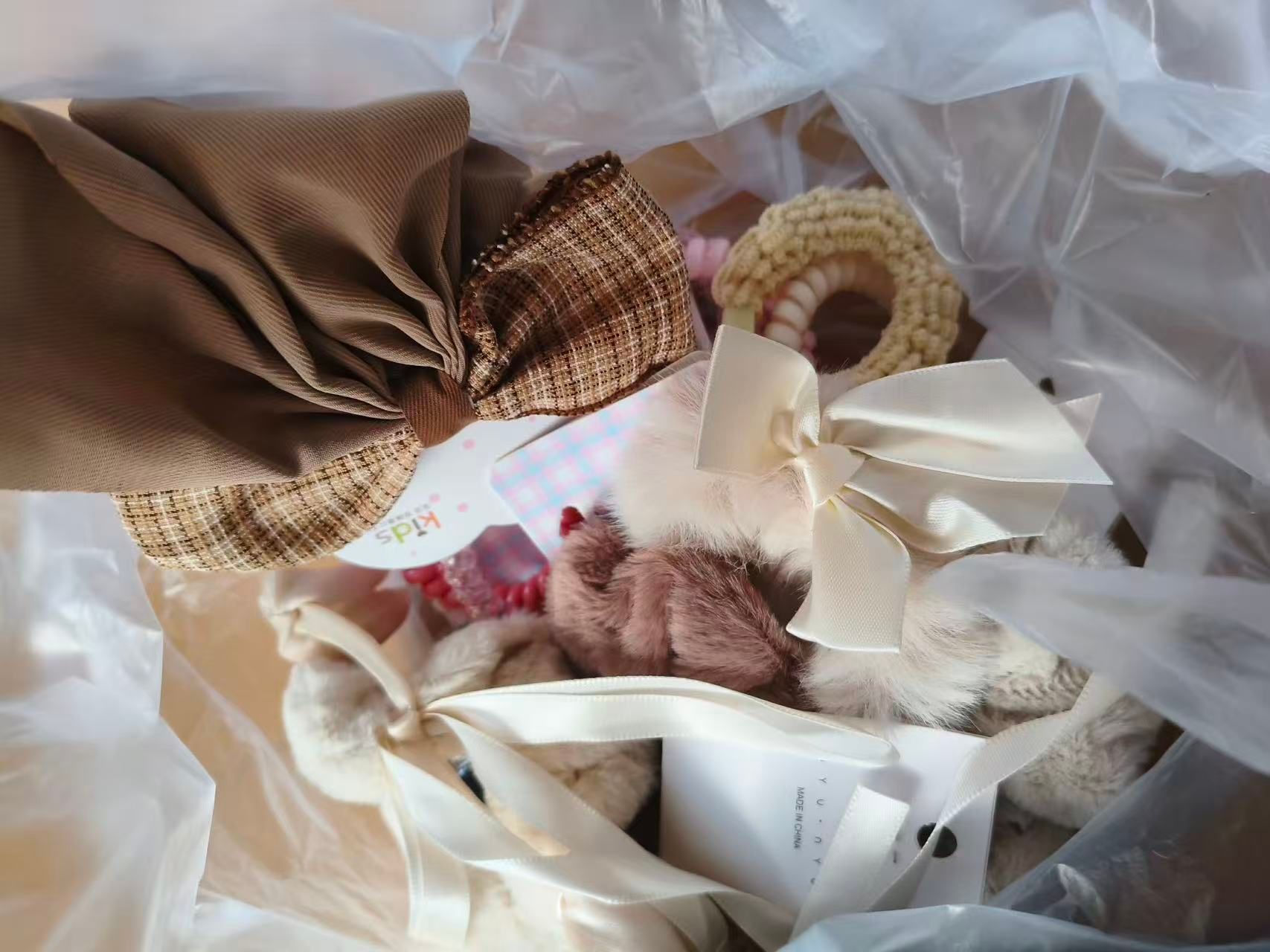Fabric pouches, scrunchies and small plush items gathered together inside a clear plastic bag.